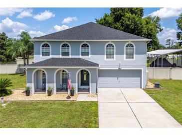 Two-story home with gray siding, arched entryway and landscaping at 7425 Lake Marni Ct, Mount Dora, FL 32757