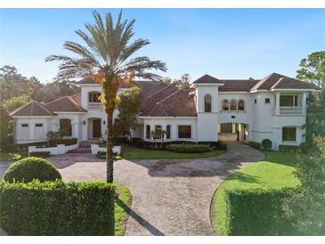 Elegant two-story home with tile roof, manicured landscaping, and circular driveway at 15008 Pendio Dr, Bella Collina, FL 34756