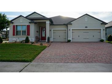 House with a three-car garage, brick paver driveway, and nicely landscaped yard at 1199 Playa Del Sol Ln, Saint Cloud, FL 34771