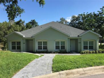 Two-unit building with green exterior and paved walkway at 124 Orange Ave, Clermont, FL 34711
