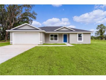 Single story home with attached garage and grassy lawn at 5 Malauka Radial Run Rd, Ocklawaha, FL 32179