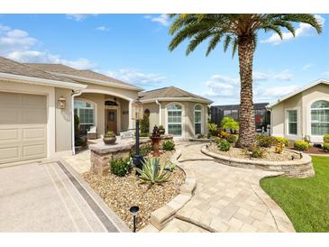 Landscaped front yard with palm trees and a paved pathway leading to the house entrance at 3520 Quietwoods Dr, The Villages, FL 32163