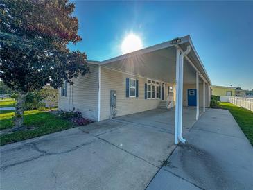 Tan single-wide manufactured home with carport and mature landscaping at 1660 Elkhart Cir, Tavares, FL 32778