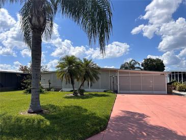 Front yard of a single-wide manufactured home with palm trees and a paved driveway at 34323 Island Dr, Leesburg, FL 34788