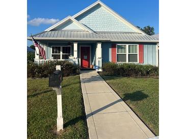 Light blue house with red shutters and a metal roof at 104 Turtle Run, Umatilla, FL 32784