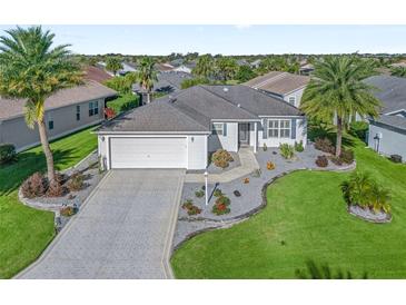 Single-story home with a paved driveway, landscaped yard and two-car garage at 3358 Quail Hollow Ct, The Villages, FL 32163