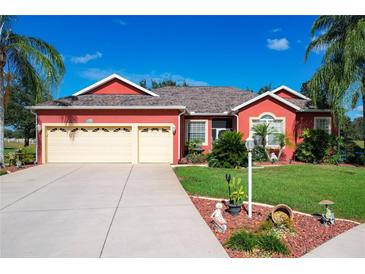 Attractive red house with three-car garage and landscaped yard at 25611 Maurepas Ln, Leesburg, FL 34748