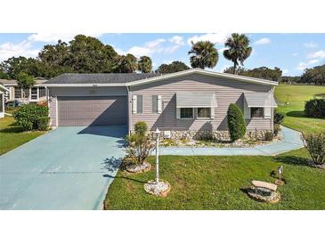 Mobile home with a single-car garage and landscaped yard at 25504 Belle Alliance, Leesburg, FL 34748