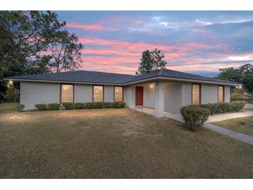 Single-story house with a red door and landscaped yard at dusk at 2101 Sw 3Rd St, Ocala, FL 34471