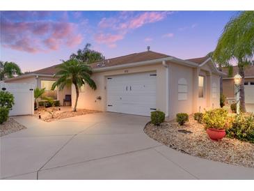 Well-maintained villa with a white garage door, landscaping, and a curved driveway at 970 Ehrhardt Pl, The Villages, FL 32162