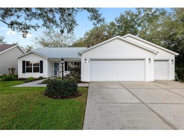 White house with 3 car garage and manicured lawn at 704 Alcott Ave, The Villages, FL 32162