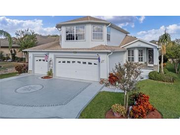 Two-story house with three-car garage, decorative driveway, and landscaped yard at 5480 Bounty Cir, Tavares, FL 32778