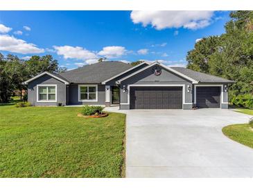 Gray house with a three-car garage and landscaped lawn at 3927 Oak Pointe Dr, Lady Lake, FL 32159