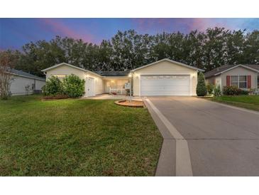 Inviting yellow home with a 2-car garage and well-manicured lawn at 1612 Staunton St, The Villages, FL 32162