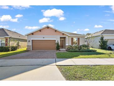 One-story home with brown garage door, landscaping, and brick pavers at 29549 Caspian St, Leesburg, FL 34748