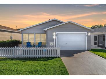 Tan house with white picket fence, one car garage, and nicely landscaped lawn at 409 Rose Croft Ter, The Villages, FL 32162
