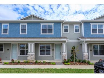 Two-story townhome with light blue exterior, stone accents, and landscaping at 13245 Peaceful Melody Dr, Winter Garden, FL 34787