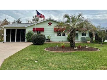 Light green house with red awnings, landscaping, and screened porch at 558 Saint Andrews Blvd, The Villages, FL 32159