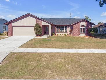 Brick and shingle ranch home with a two-car garage and landscaped yard at 7715 Indian Ridge N Trl, Kissimmee, FL 34747