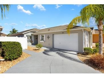 One-story home with attached garage, landscaping, and a paved driveway at 997 Oscar Ln, The Villages, FL 32162