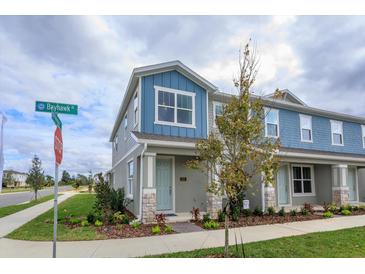 Two-story townhome with blue and gray siding, stone accents, and a front porch at 16351 Hamlin Hills Aly, Winter Garden, FL 34787