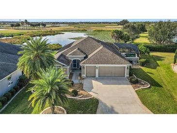 Single-story home with pool and lake view. Landscaped yard and attached garage at 1532 Resthaven Way, The Villages, FL 32163