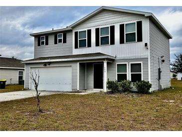 Two-story house with gray siding, black shutters, and a white garage door at 209 Hyacinth Ct, Kissimmee, FL 34759
