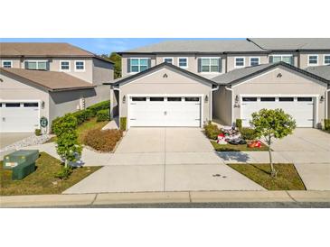Front view of townhome with two-car garage and landscaped yard at 8512 Magnificent Ln, Groveland, FL 34736