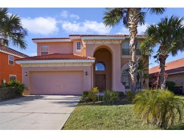 Two-story house with a pink facade, a three-car garage, and lush landscaping at 151 Rubino Dr, Davenport, FL 33837