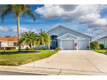 Two-car garage, light gray house with palm trees and manicured lawn at 5717 Illumination Ln, Leesburg, FL 34748