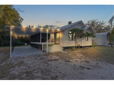 Charming white house with covered porch and string lights, situated on a spacious lot at 13536 Se Sunset Harbor Rd, Weirsdale, FL 32195