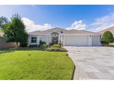 Single-story home with a three-car garage and landscaped yard at 747 Bradford Loop, The Villages, FL 32163