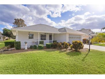 Brick ranch home with carport, mature landscaping, and a spacious front yard at 950 Beaver Run, Tavares, FL 32778