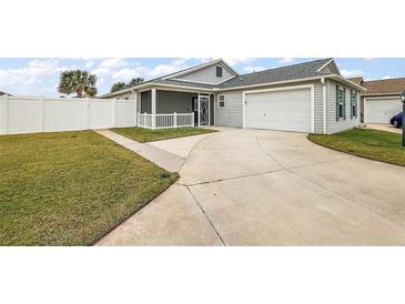 View of backyard with grassy area, white fence, and a concrete driveway at 4056 Venetian Ln, The Villages, FL 32163