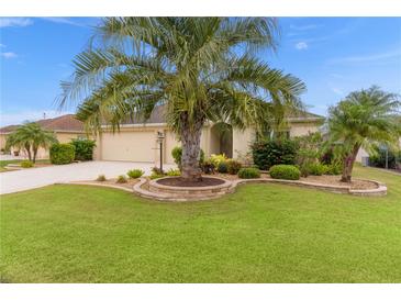 Landscaped yard with palm tree and stone accents in front of a tan house at 469 Pinfish Ct, The Villages, FL 32163