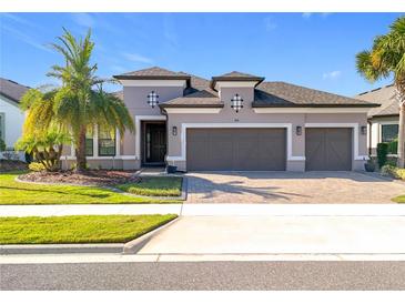 Two-story house with three-car garage, neutral color scheme, and landscaping at 1216 Zeek Ridge St, Clermont, FL 34715