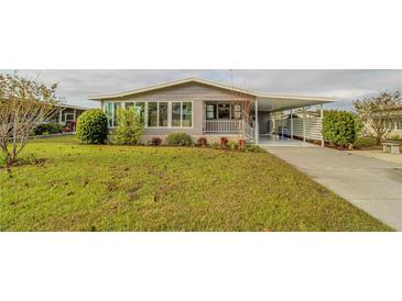 Gray single-story home with carport and landscaped lawn at 1431 Mohawk Cir, Tavares, FL 32778