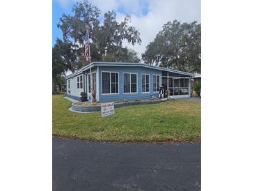 Cute blue home with landscaped lawn and carport at 30 Riverview Dr, Fruitland Park, FL 34731