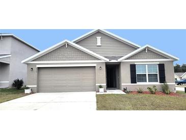 One-story house with gray siding, two-car garage, and landscaping at 716 Se 64Th Ter, Ocala, FL 34472