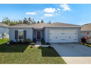One-story home with gray siding, white garage door, and landscaped lawn at 1109 Catskill Dr, Haines City, FL 33844
