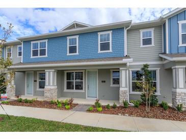 Two-story townhome with blue and gray siding, stone accents, and a walkway at 16484 Tangerine Mesa Dr, Winter Garden, FL 34787