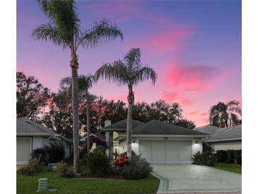 Inviting house exterior at dusk, featuring a two-car garage and palm trees at 21737 Royal St Georges Ln, Leesburg, FL 34748