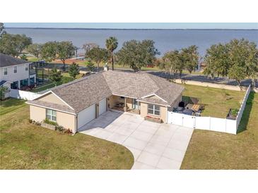 Single-story home with lake view, fenced yard, and two-car garage at 3219 Landing Vw, Tavares, FL 32778