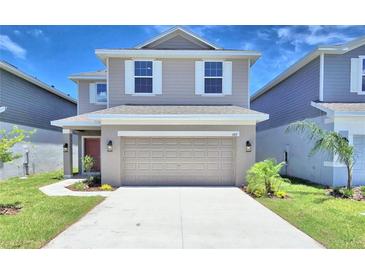 Two-story house with beige siding, a two-car garage, and landscaping at 1417 Leamington Ln, Winter Haven, FL 33884