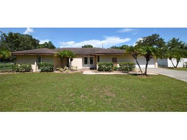 Tan single-story house with a large yard, double doors, and a white garage door at 2646 Handley Blvd, Lakeland, FL 33803