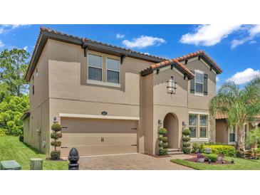 Two-story house with a tan exterior, brown roof, and manicured landscaping at 4184 Prima Lago Cir, Lakeland, FL 33810