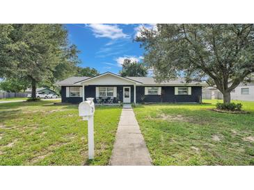 Ranch-style home with dark exterior, white trim, and a well-manicured lawn at 1206 Price Ave, Auburndale, FL 33823