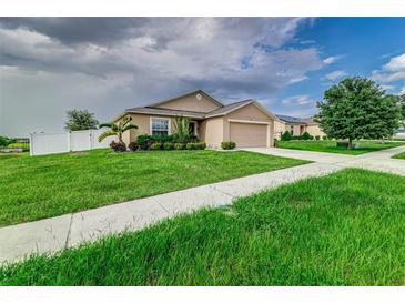 Tan one-story house with a two-car garage at 653 Hidden Lakes Ct, Haines City, FL 33844