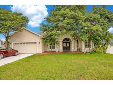 Tan house with a red car parked in the driveway at 2948 Vintage View Cir, Lakeland, FL 33812