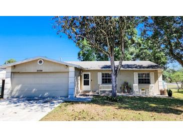 Tan one-story house with a garage and mature tree in the front yard at 2036 E Gachet Blvd, Lakeland, FL 33813